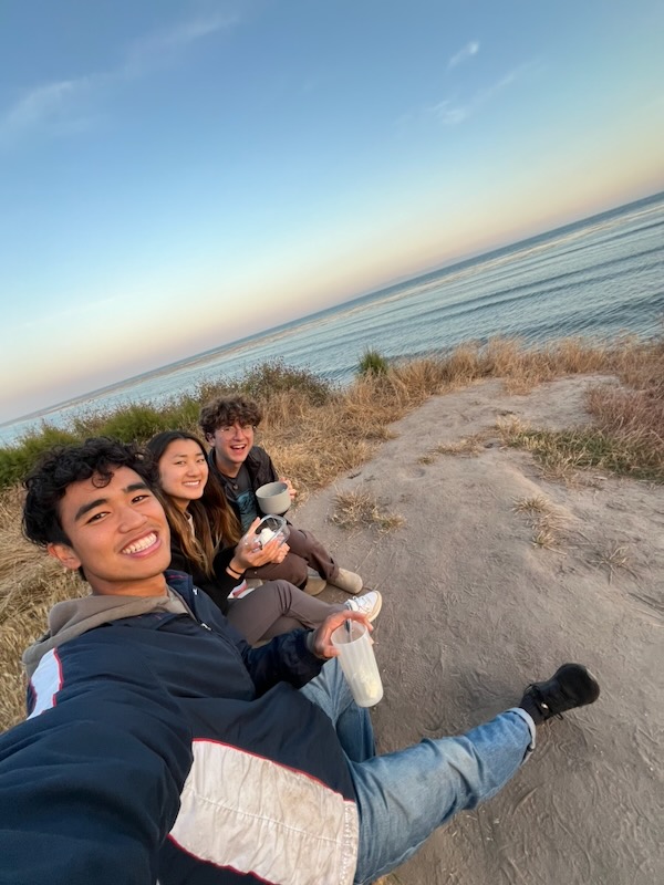 Andrew Tolu and friends sitting on the Isla Vista bluffs at sunset overlooking the ocean.