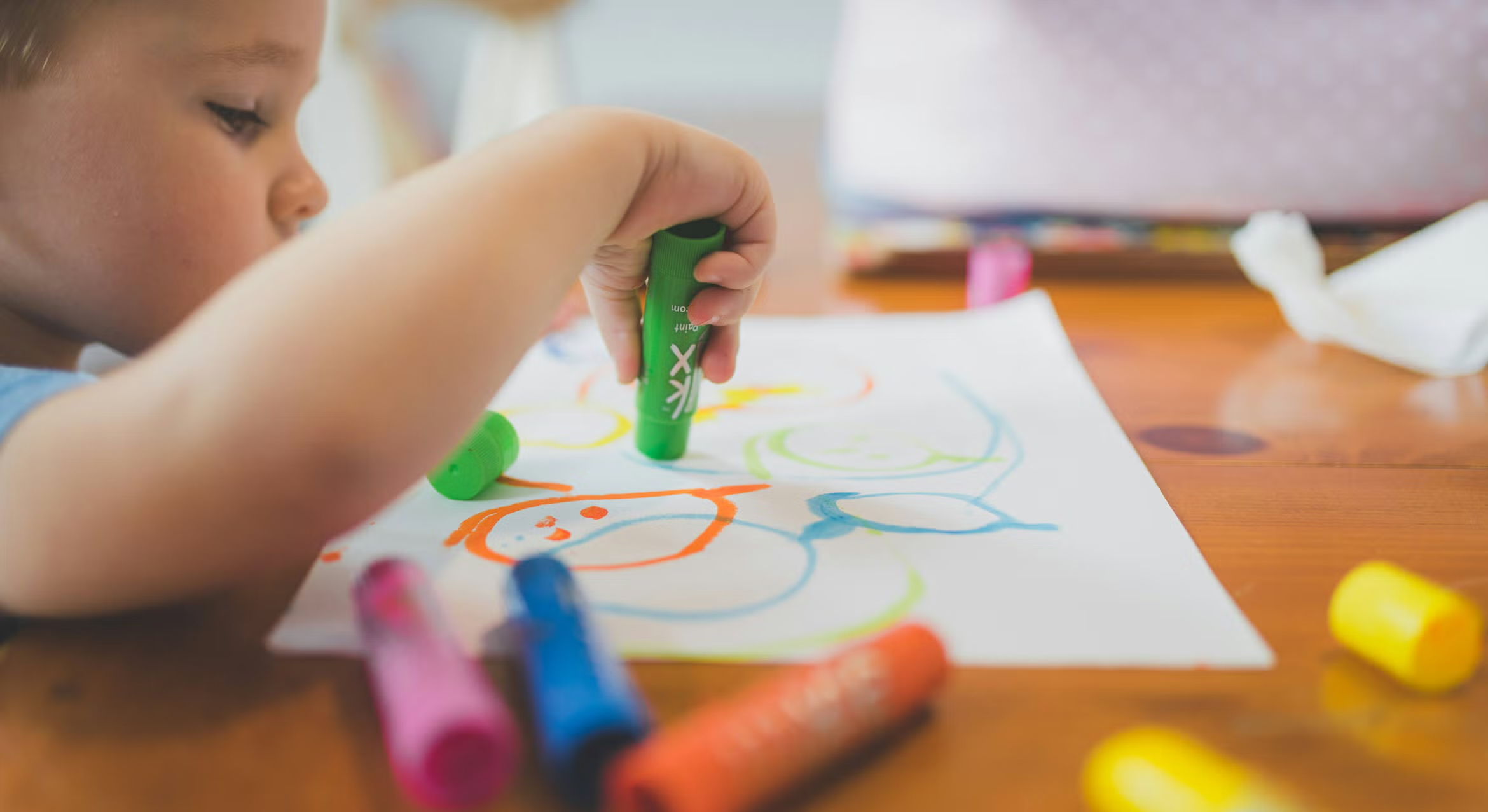 A close-up shot of a young child's hand using markers on a drawing.